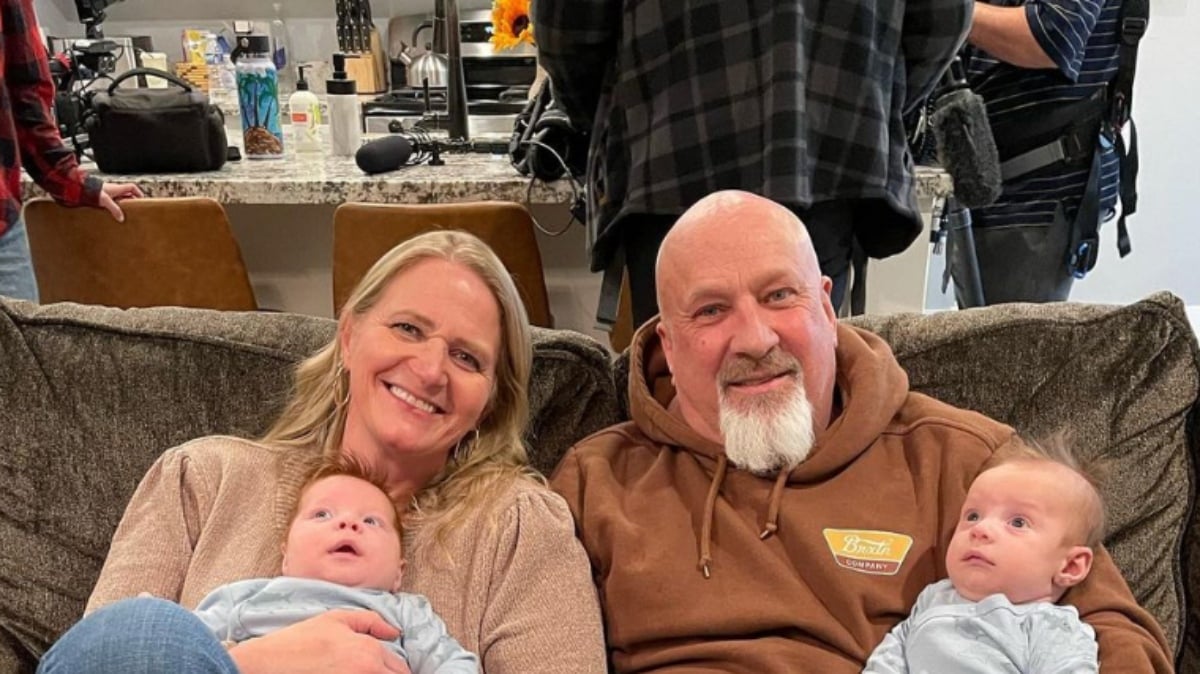 A photo of 'Sister Wives' star Christine Brown sitting with her new boyfriend David Woolley on her couch holding her grandchildren.