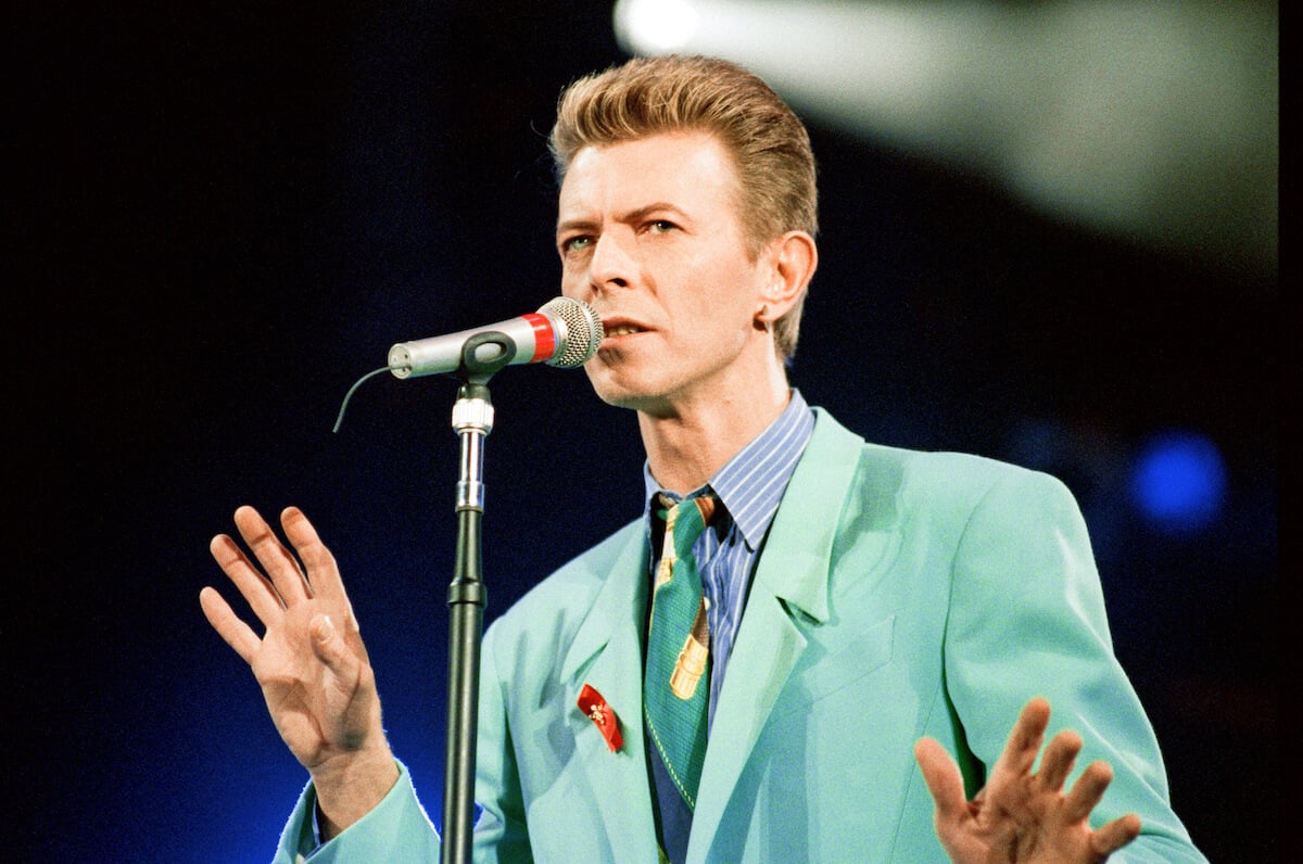 David Bowie standing in front of a microphone with his hands up