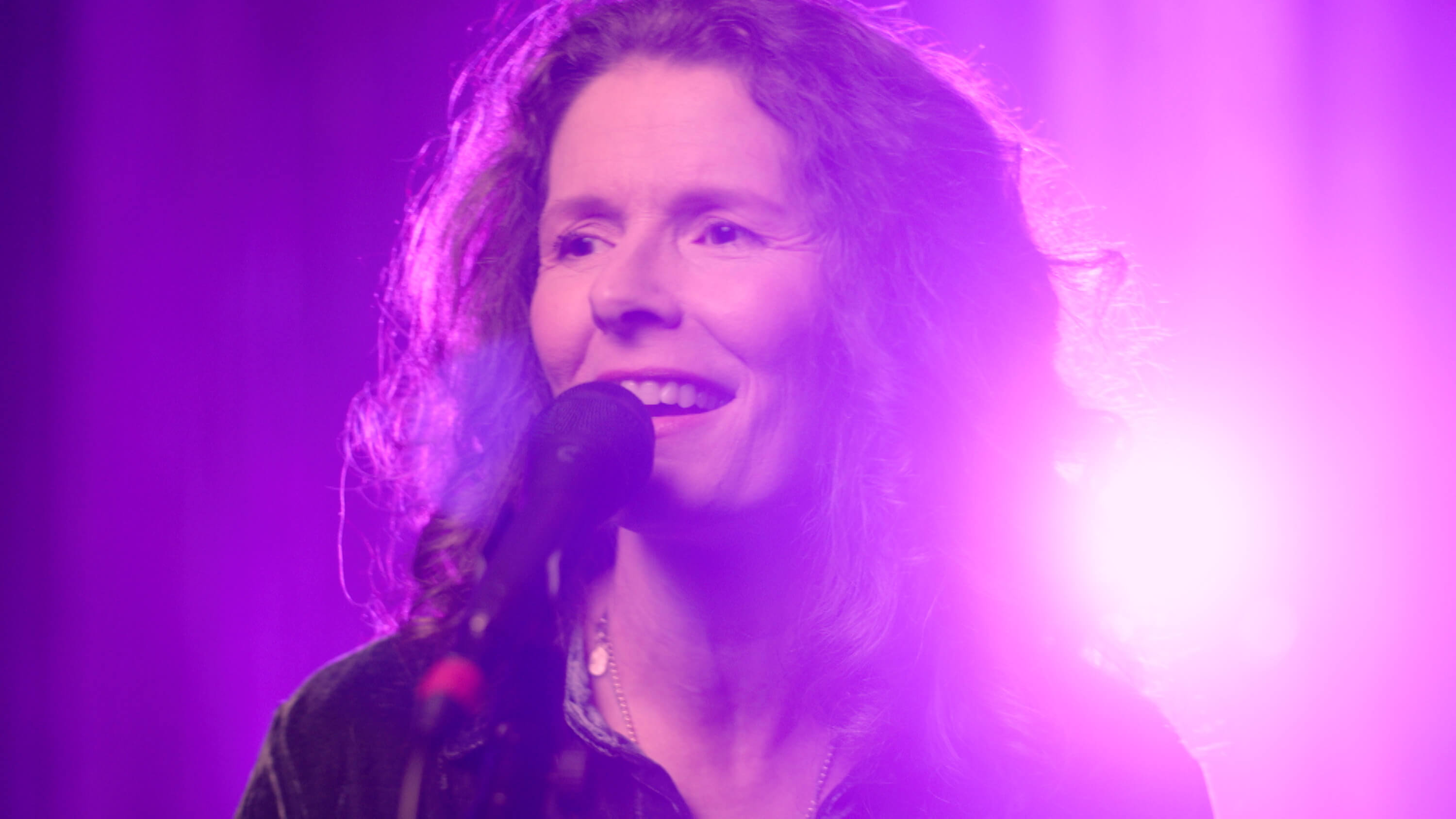 Edie Brickell in front on a microphone