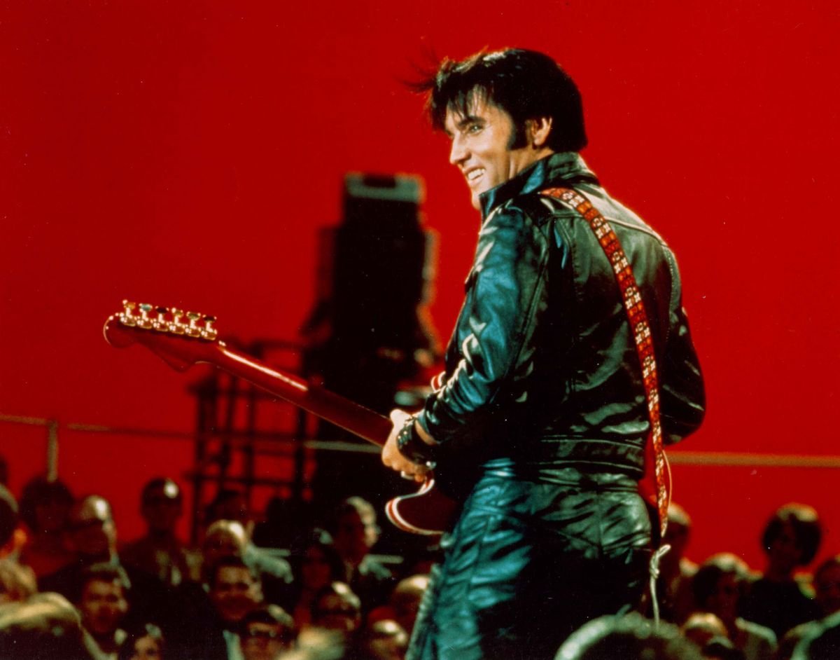 Elvis smiles while playing a guitar