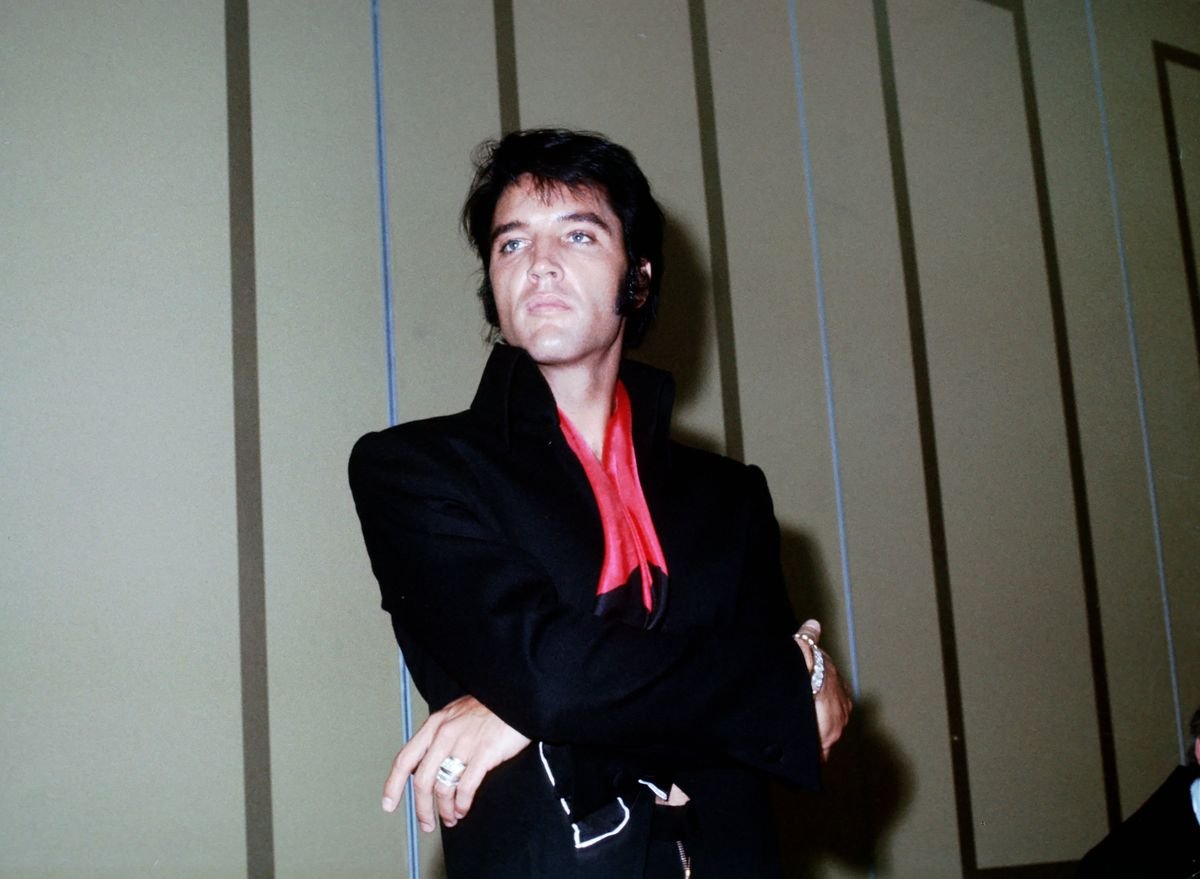 Elvis stands against a wall