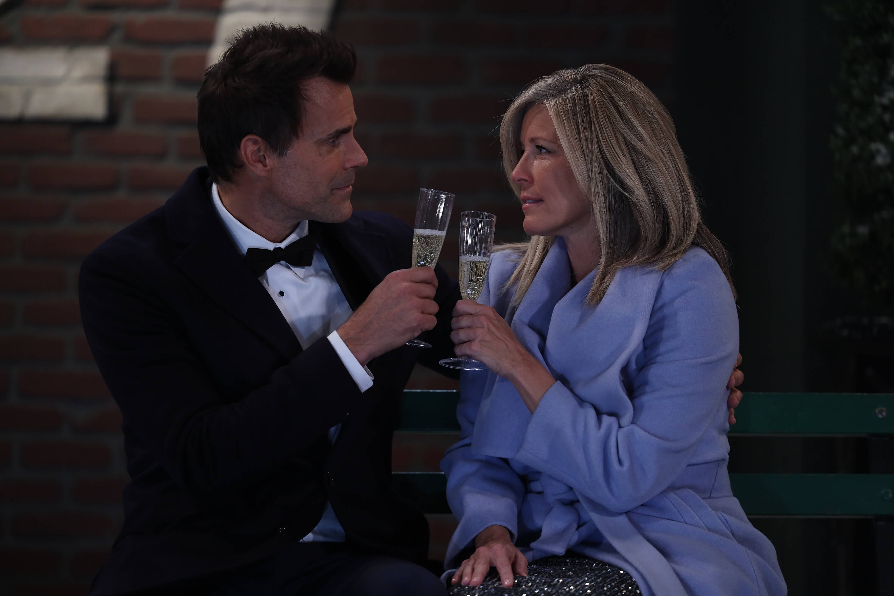 'General Hospital' stars Cameron Mathison and Laura Wright sitting on a bench in a scene from the soap opera.