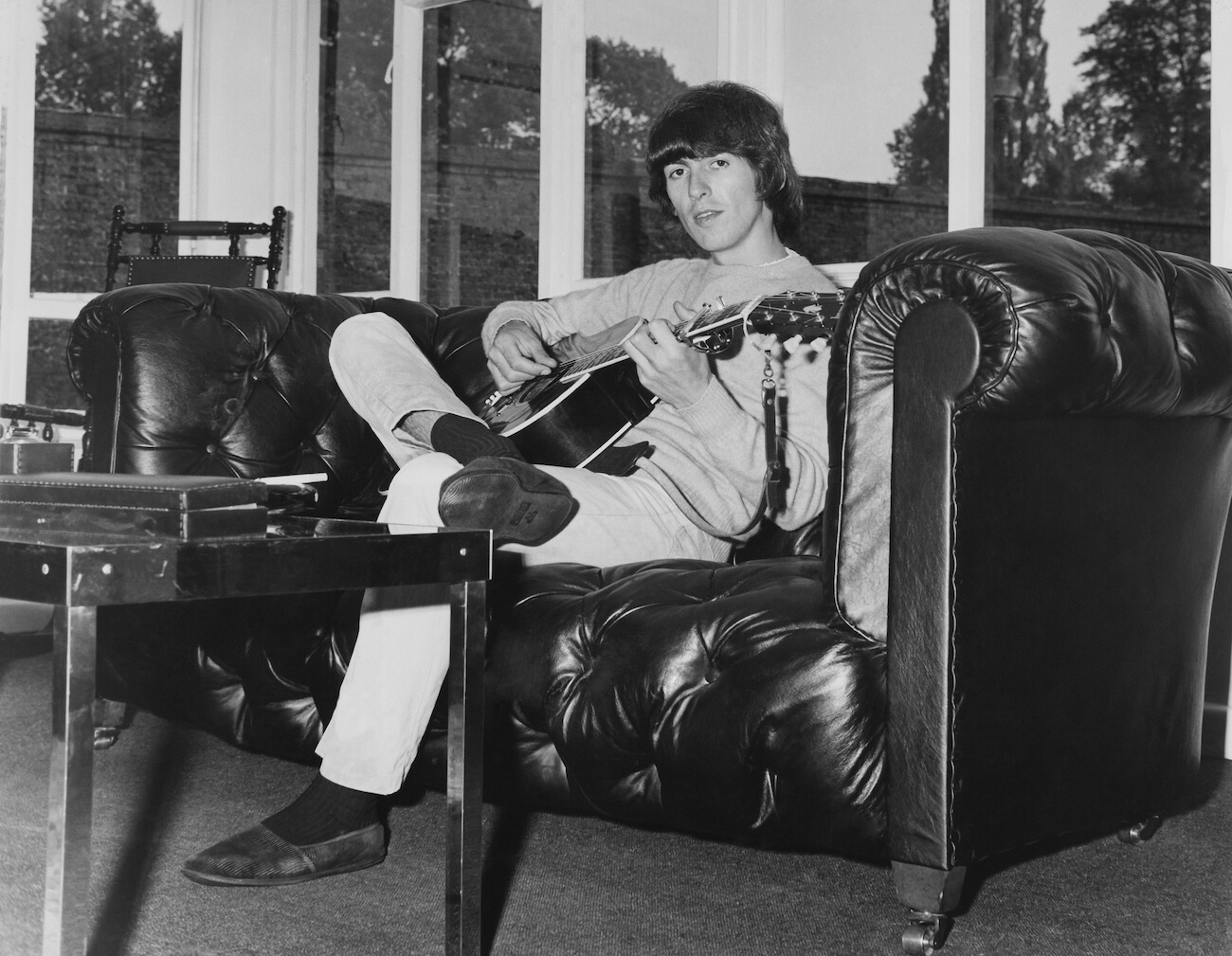 George Harrison playing guitar at home in 1965.