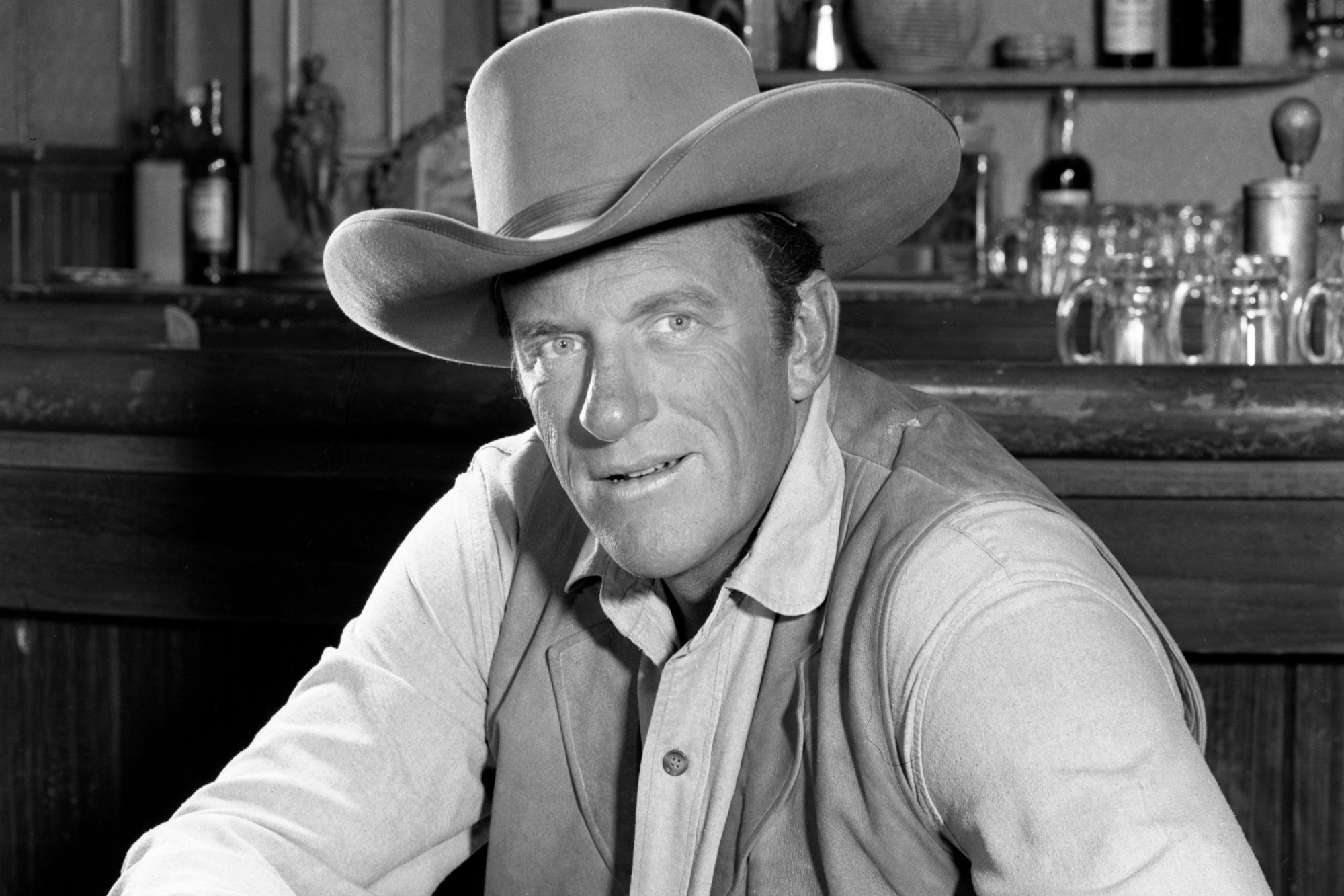 'Gunsmoke' James Arness as U.S. Marshal Matt Dillon in a black-and-white portrait in front of a wooden tabletop