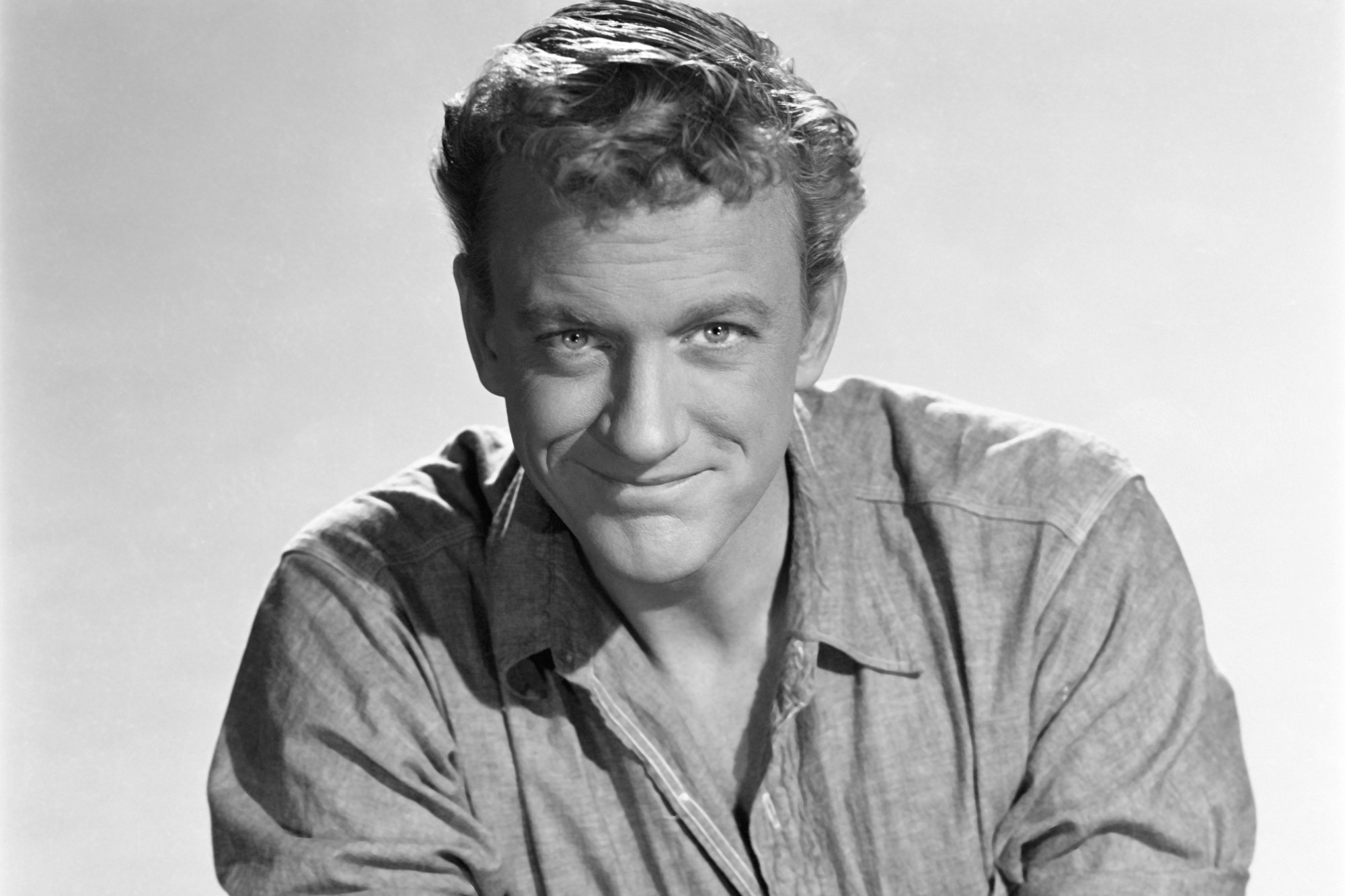 'Gunsmoke' actor James Arness, who represented Westerns before 'Deadwood' in a black-and-white publicity picture, smiling.