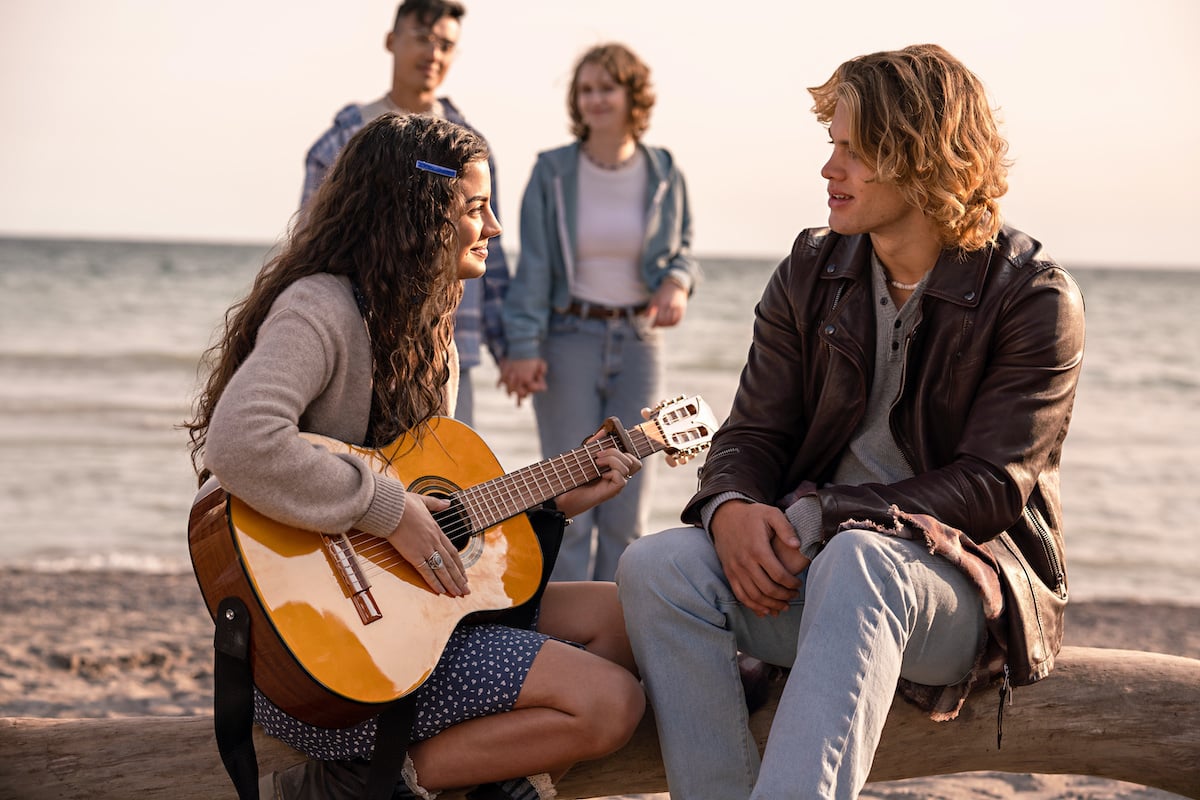 Alice playing the guitar on a beach in an episode of 'The Way Home'