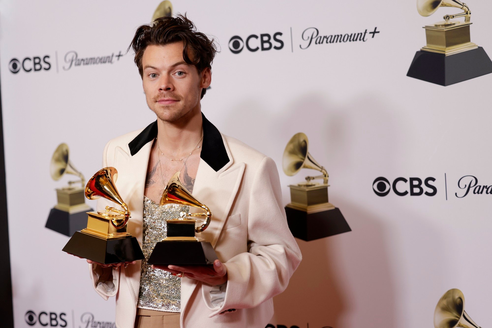 Harry Styles holds up two Grammy Awards