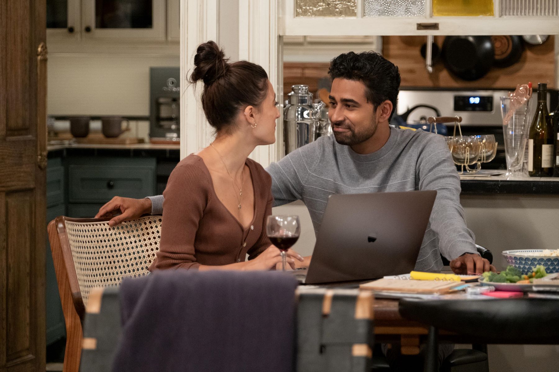 Ashley Reyes as Hannah and Suraj Sharma as Sid in 'How I Met Your Father' Season 2 Episode 3, 'The Reset Button.' Hannah wears a brown button-up sweater. Sid wears a light gray striped sweater.