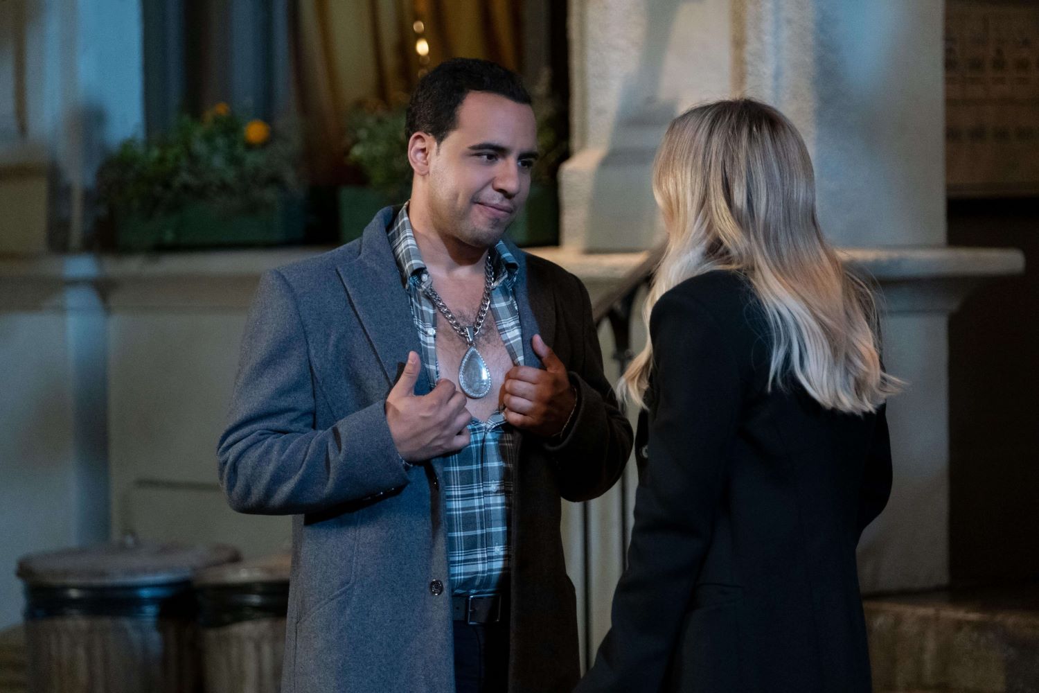 Victor Rasuk and Hilary Duff, in character as Oscar and Sophie in 'How I Met Your Father' Season 2 Episode 6, share a scene. Oscar wears a gray coat over a green and white plaid button-up shirt and huge diamond necklace. Sophie wears a black coat.