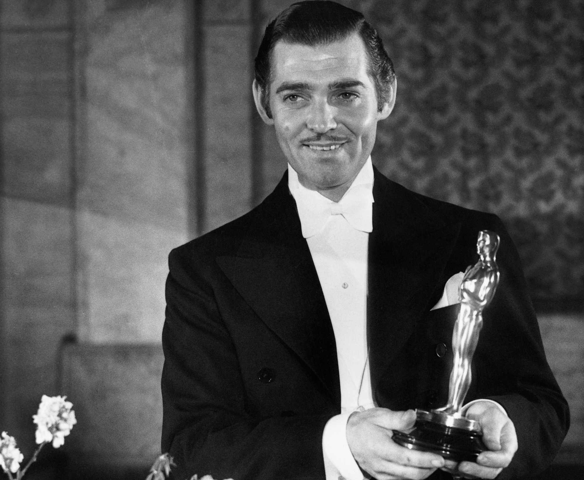 'It Happened One Night' Clark Gable holding an Oscar, smiling, while wearing a tux