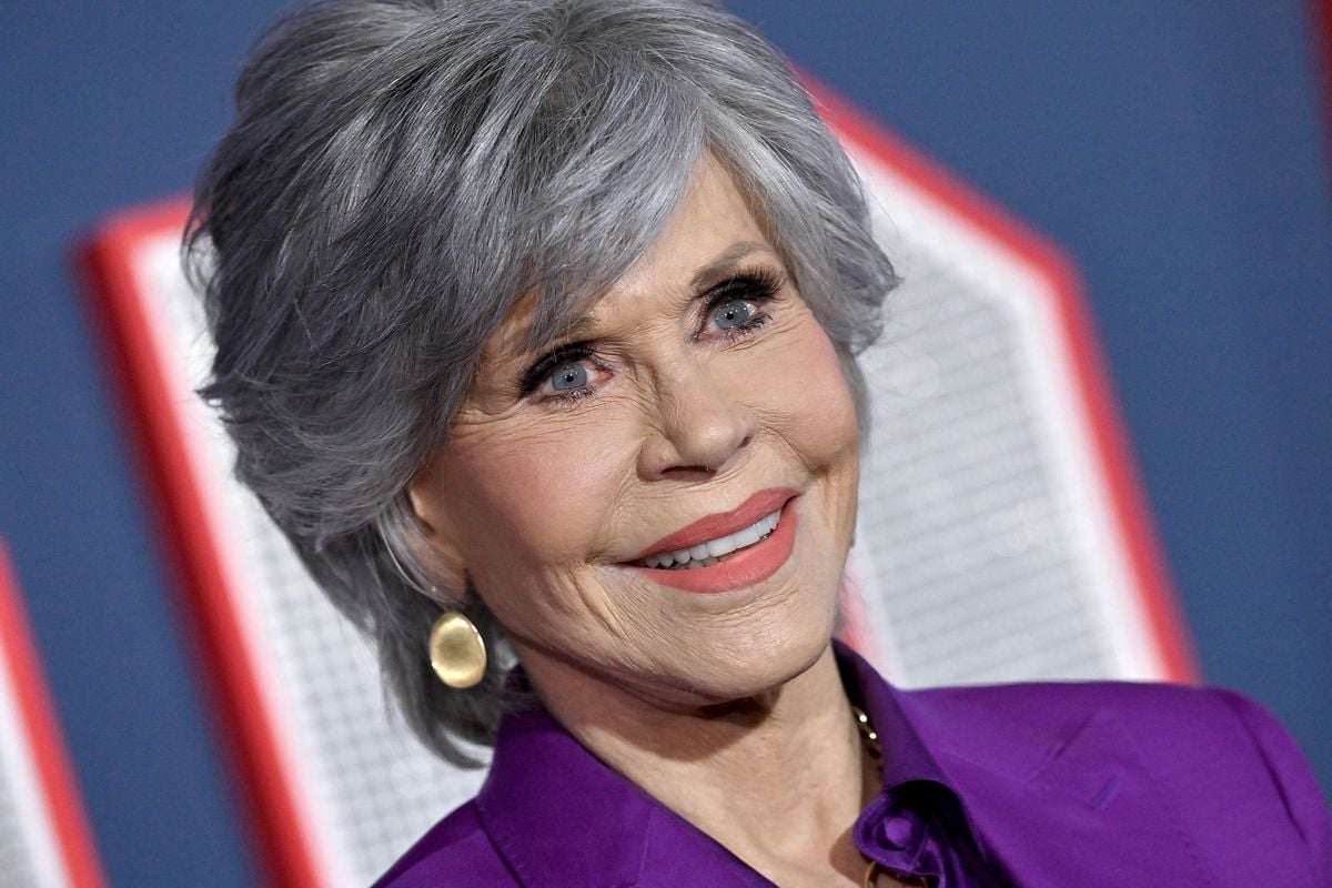 Jane Fonda smiles for photos in front of a backdrop featuring the "80 for Brady" logo