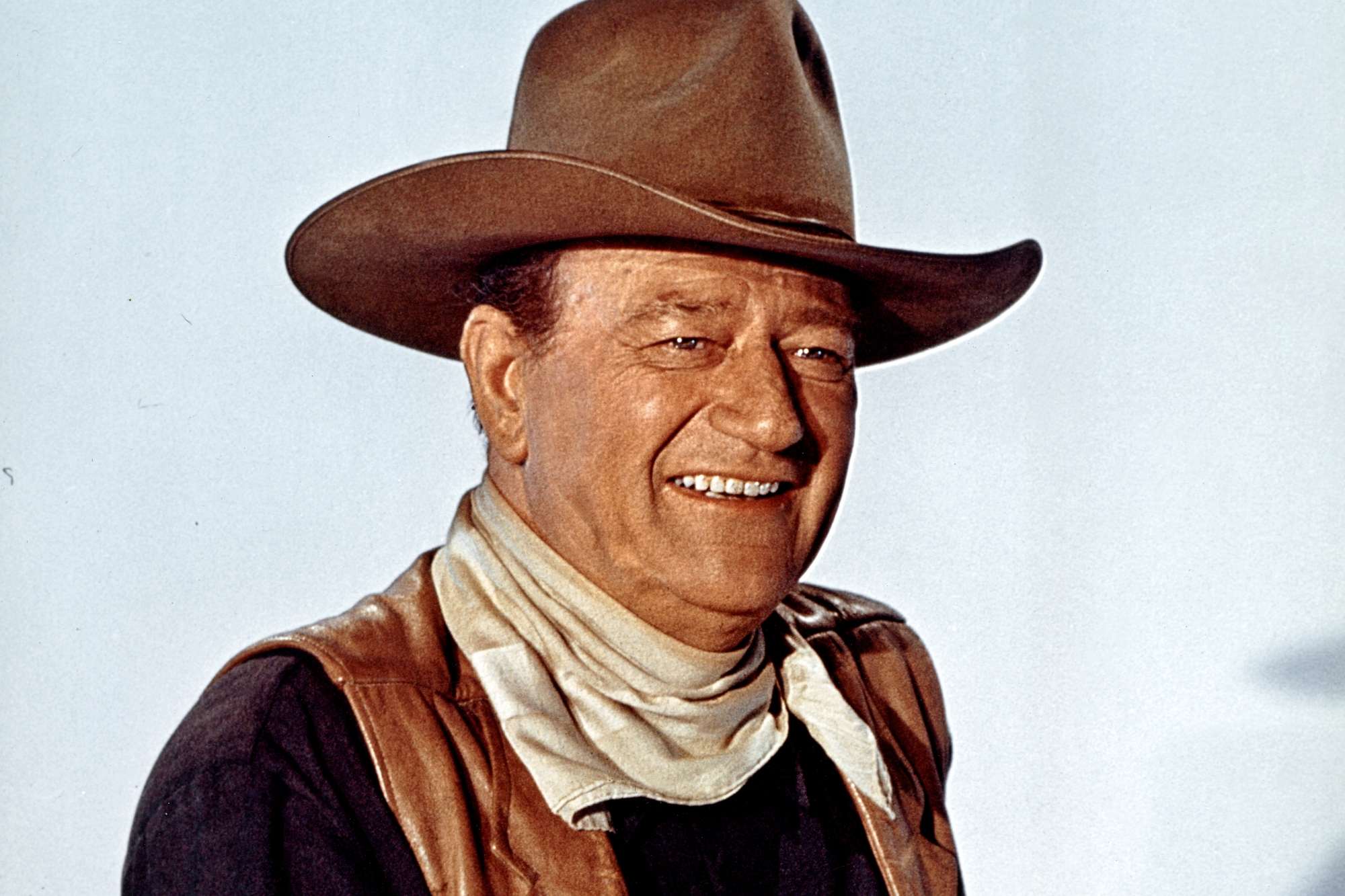 John Wayne starring in Western movies smiling, wearing a cowboy costume