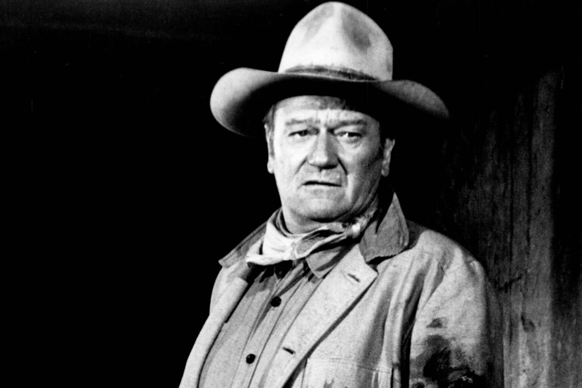 John Wayne, who starred in Western and war films. He has a serious look, wearing a Western costume.