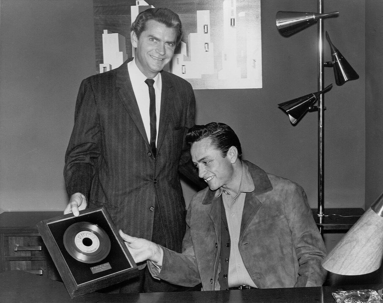 Sun Records founder Sam Phillips (left) gives Johnny Cash a framed record of his song 'I Walk the Line' in 1956.