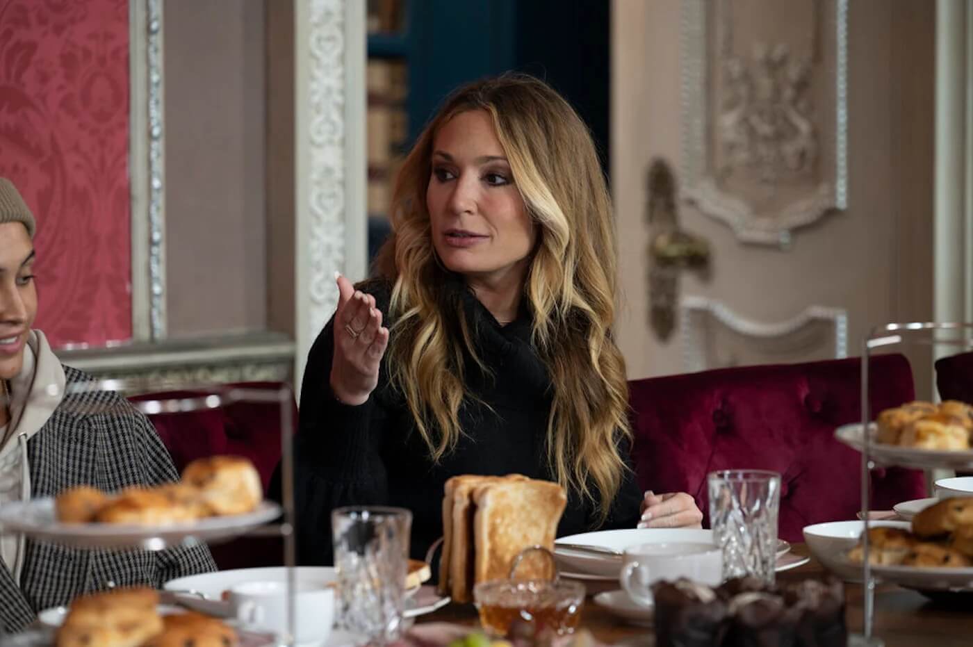 'The Traitors' stars Kate Chastain and Brandi Glanville. Kate is seen here sitting at a table in a production still from the series.