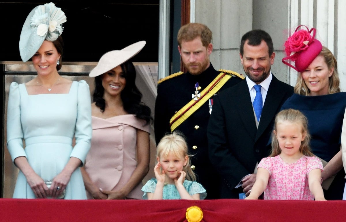 Kate Middleton, Meghan Markle, Prince Harry, Peter Phillips, and Autumn Kelly with their children standing on the balcony of Buckingham Palace in 2018
