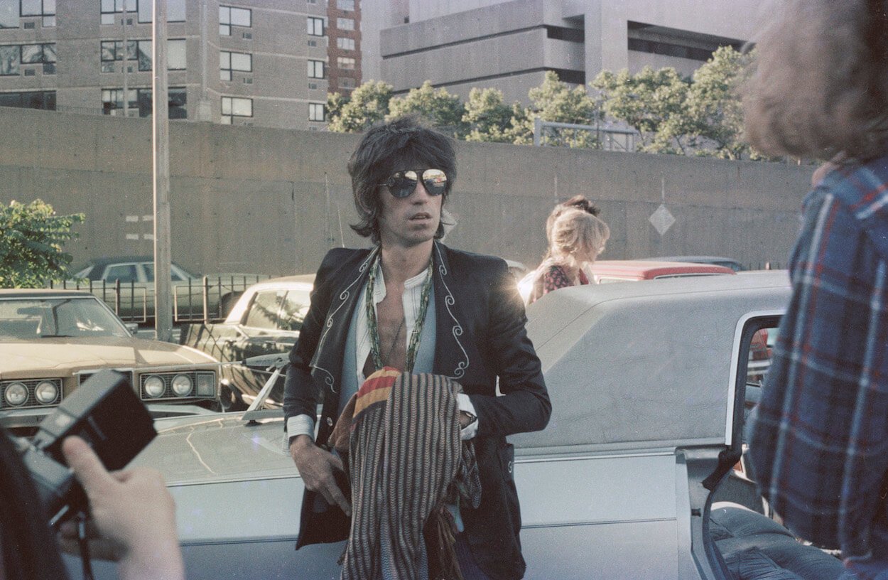 Rolling Stones guitarist Keith Richards encounters fans and media in 1975 while standing next to a car.