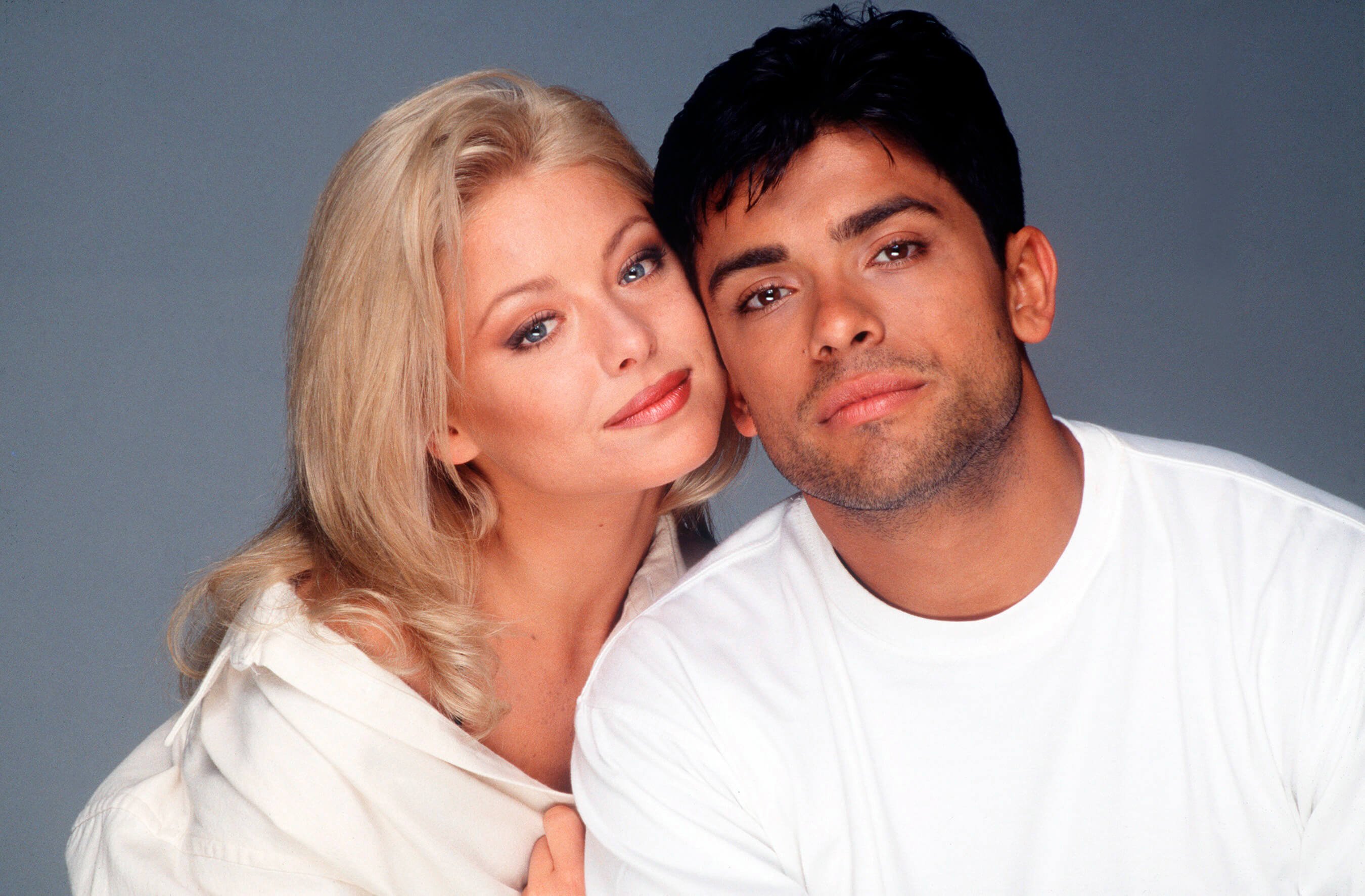 'All My Children' stars Kelly Ripa and Mark Consuelos dressed in white; posing for a photo.