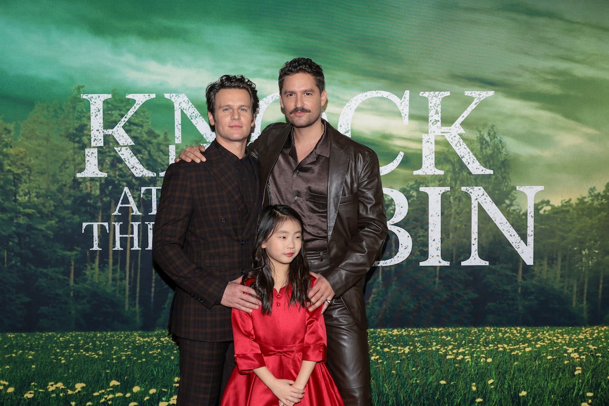 Ben Aldridge, Kristen Cui and Jonathan Groff pose in front of the "Knock at the Cabin" logo