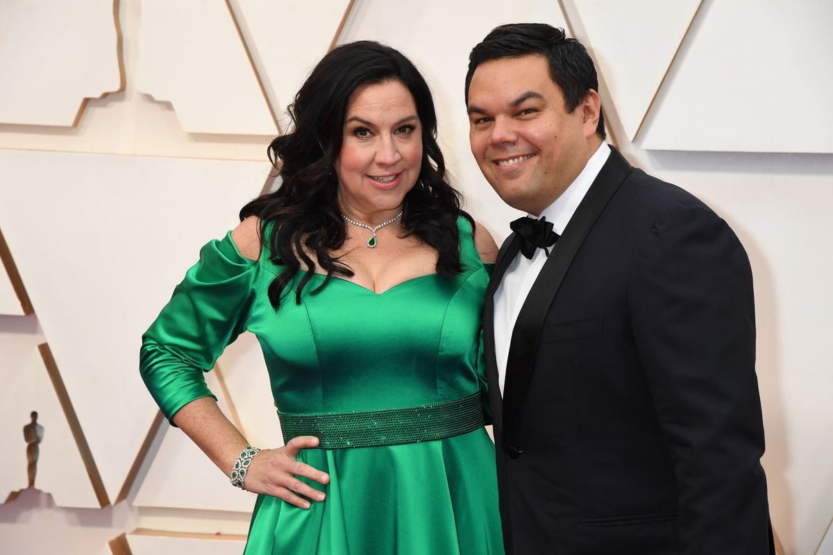 Kristen Anderson-Lopez and Robert Lopez pose for photos on the Oscars red carpet.