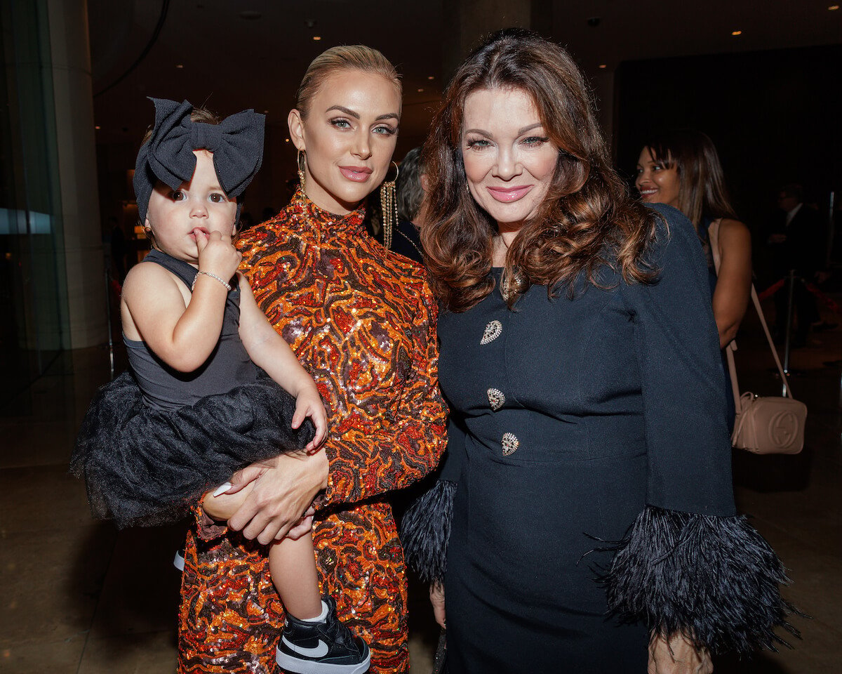 Lala Kent holding her baby daughter and standing next to Lisa Vanderpump