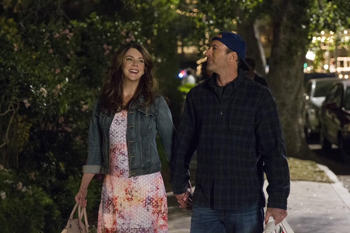 Lorelai and Luke walk down the street holding hands in an episode of 'GIlmore GIrls: A Year in the Life'