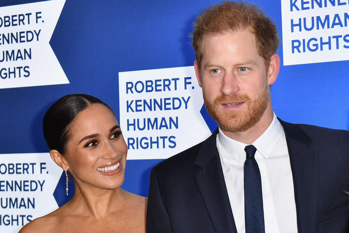 Meghan Markle and Prince Harry smile and look on