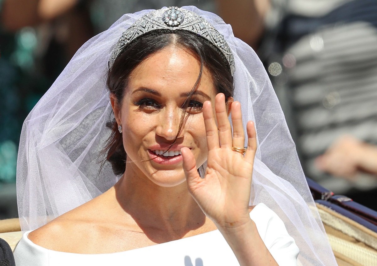 Meghan Markle waves from carriage during the procession after royal wedding