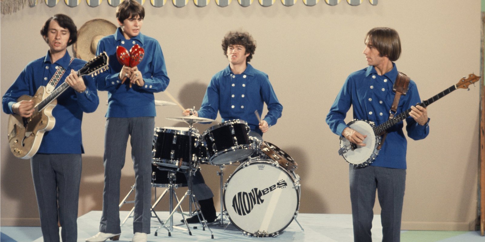 Mike Nesmith, Davy Jones, Micky Dolenz and Peter Tork wearing matching blue shirs and grey pants.
