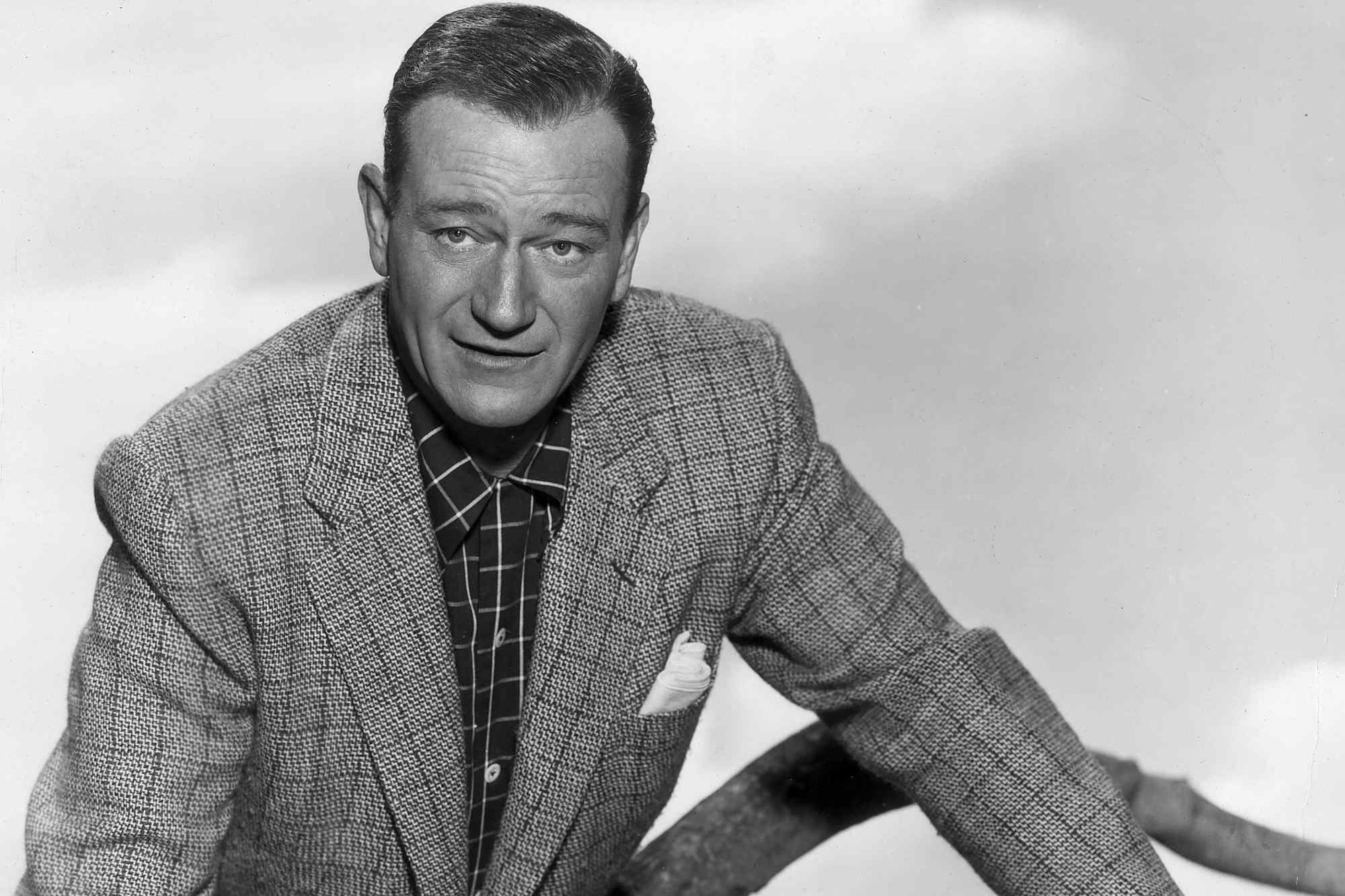 Movie star John Wayne wearing a suit with a slight smile on his face
