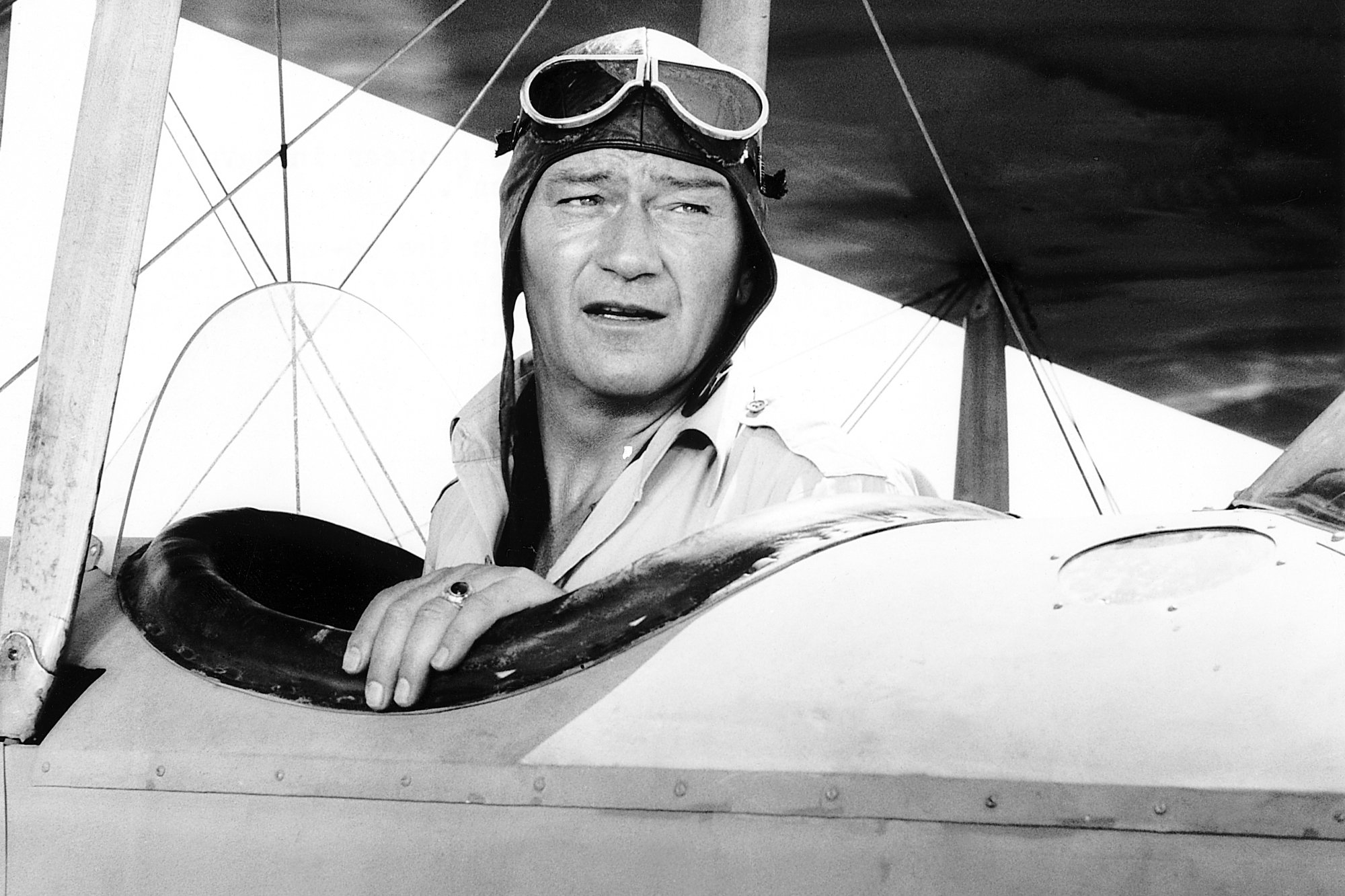 Movie star John Wayne sitting in the cockpit of a jet, looking over his shoulder