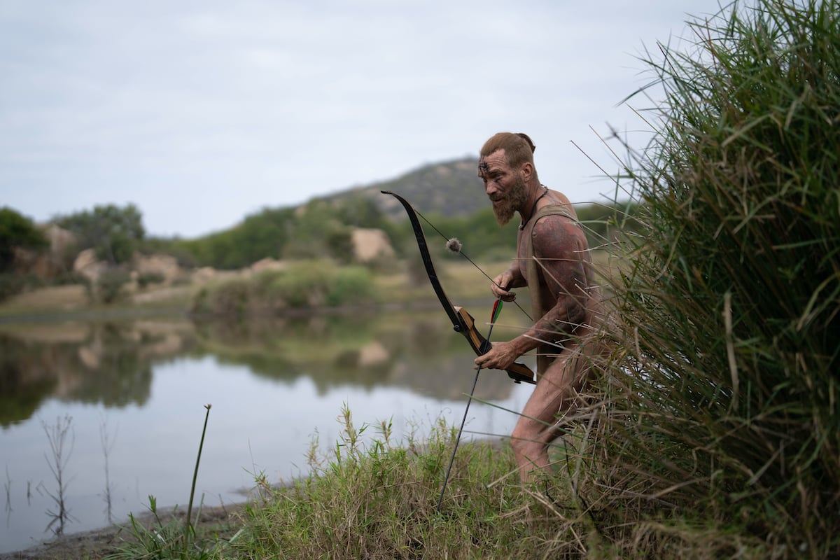 Man holding a bow and arrow on 'Naked and Afraid' Season 15