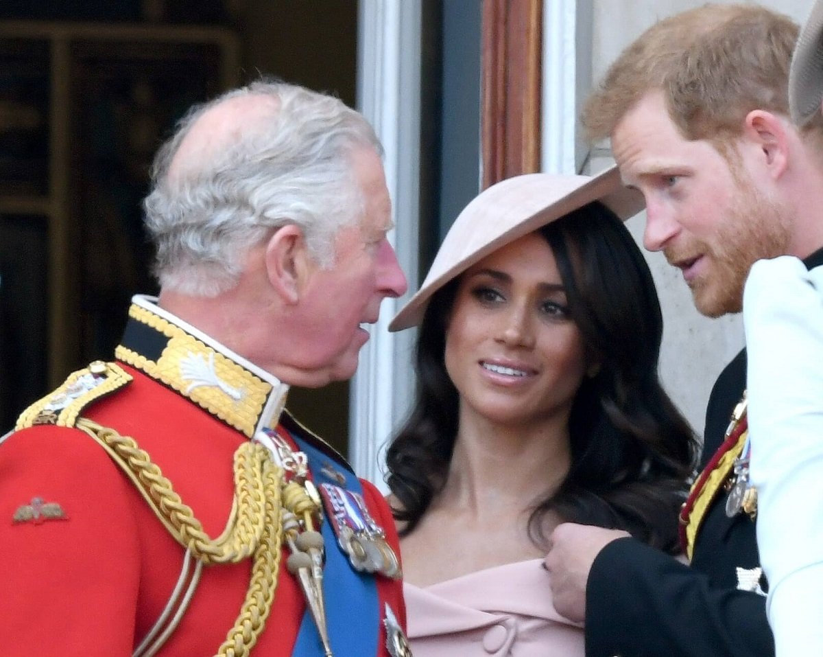 Now-King Charles III, Meghan Markle, and Prince Harry standing on the balcony of Buckingham Palace during Trooping The Colour 2018