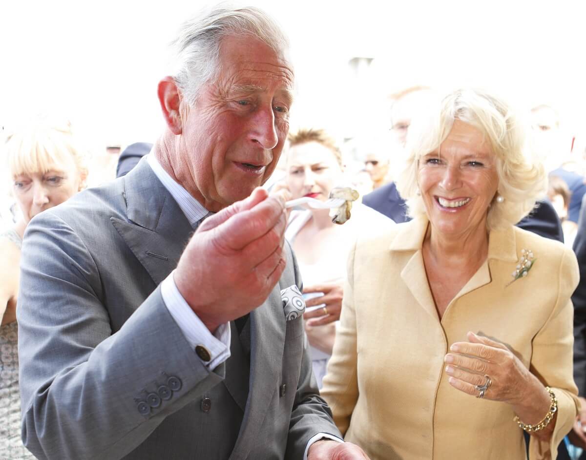 Now-King Charles III trying food as Camilla Parker Bowles looks on during their visit to the Whitstable Oyster Festival
