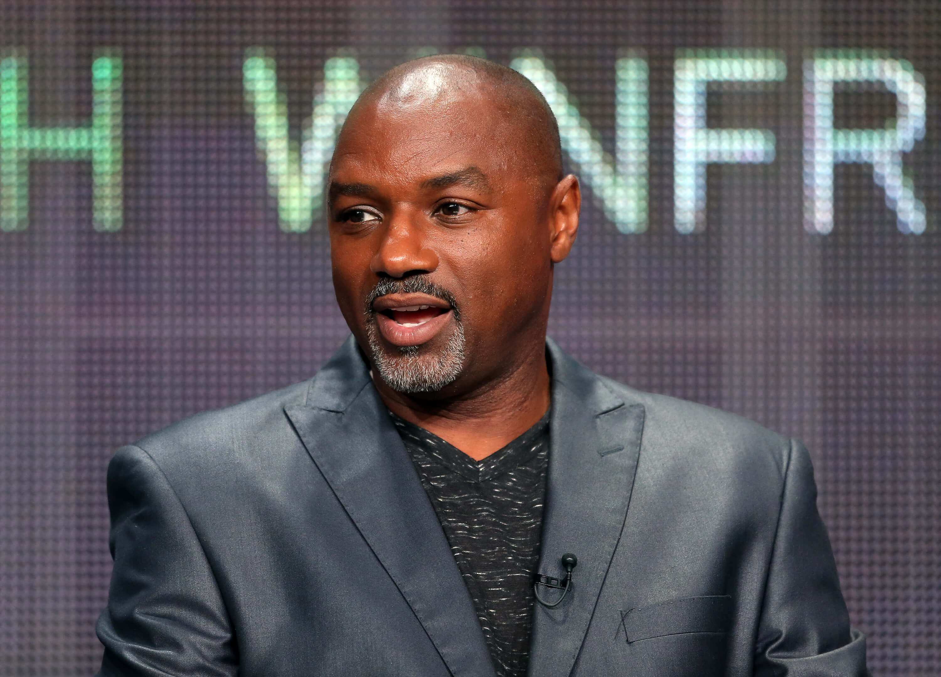 'Passions' star Rodney Van Johnson dressed in a grey suit, speaking during a panel discussion.