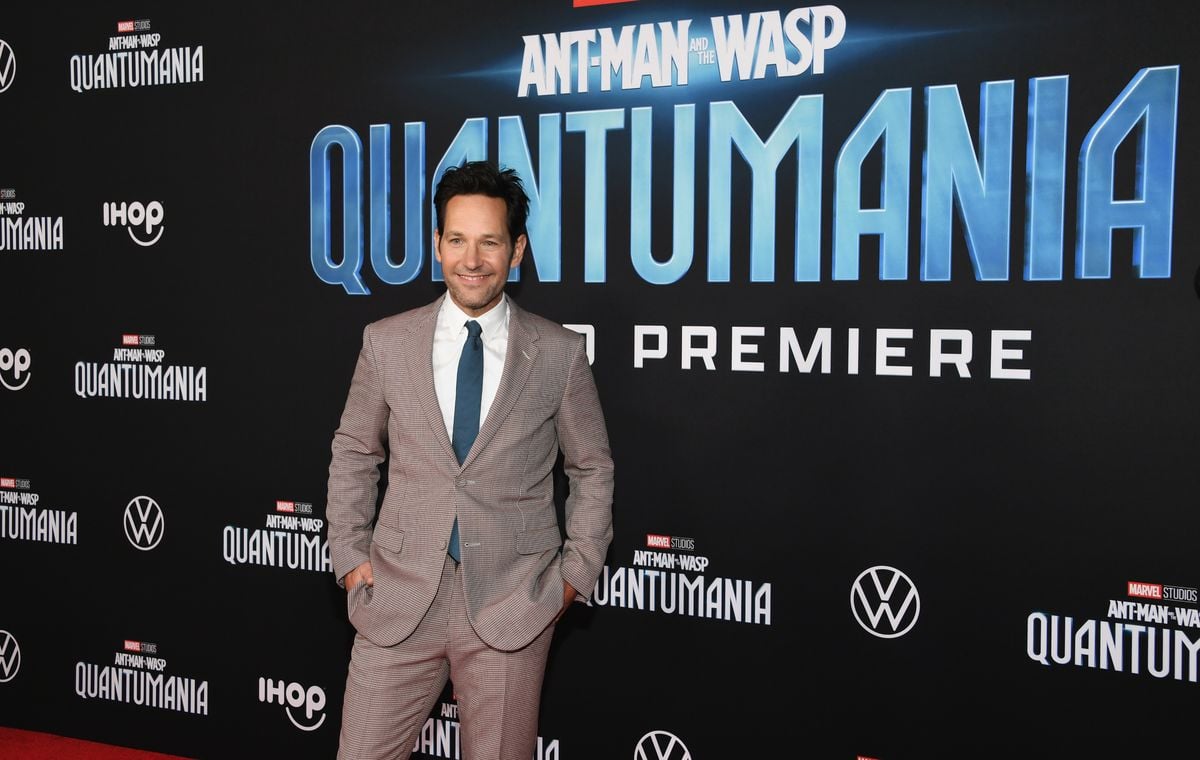 Paul Rudd poses in front of a backdrop that features the logo for “Ant-Man And The Wasp: Quantumania"
