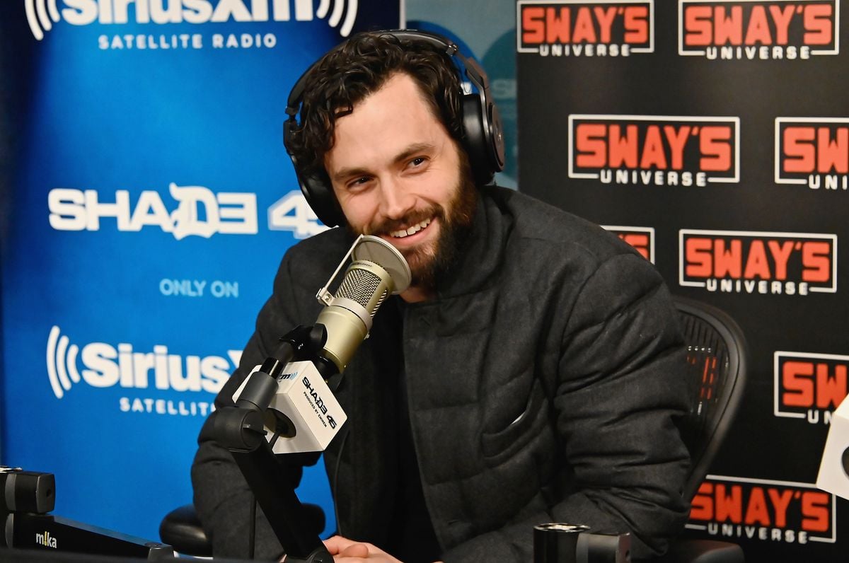 Penn Badgley answers questions while speaking into a microphone.