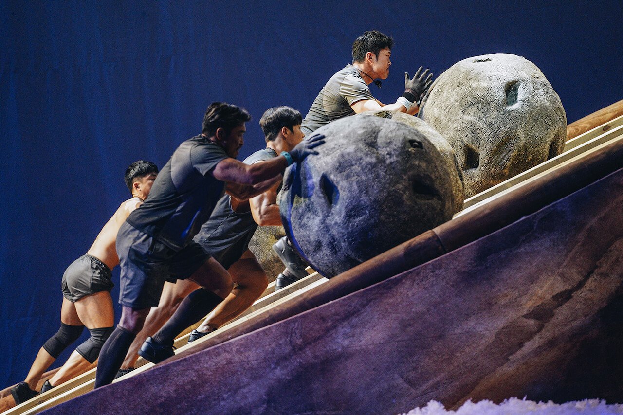 Jung Hae-min, Yun Sung-bin, Ma Sun-ho, and Choo Sung-hoon push a boulder uphill on 'Physical 100'.