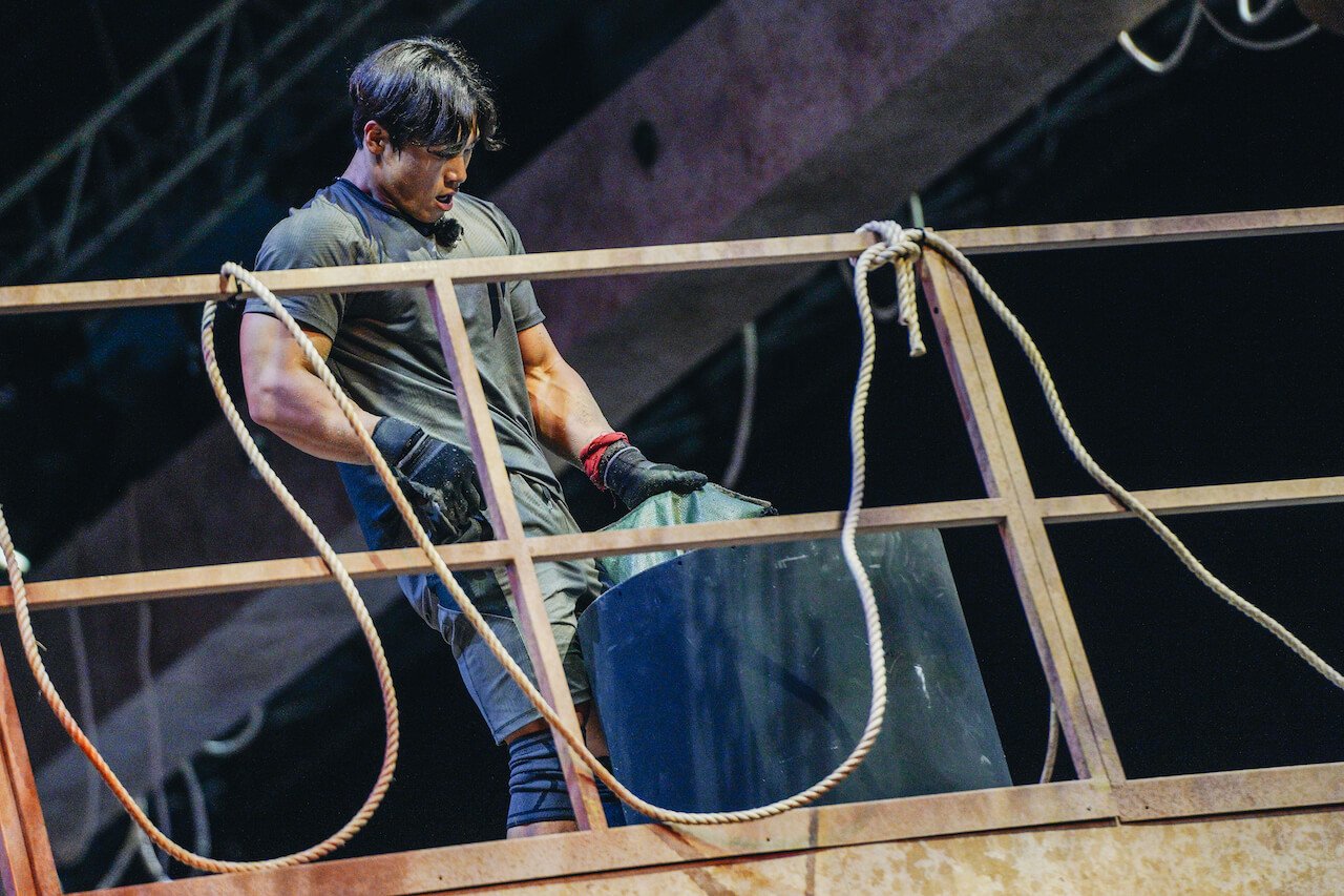 Yun Sung-bin empties a sand bag into a bin on 'Physical 100'.