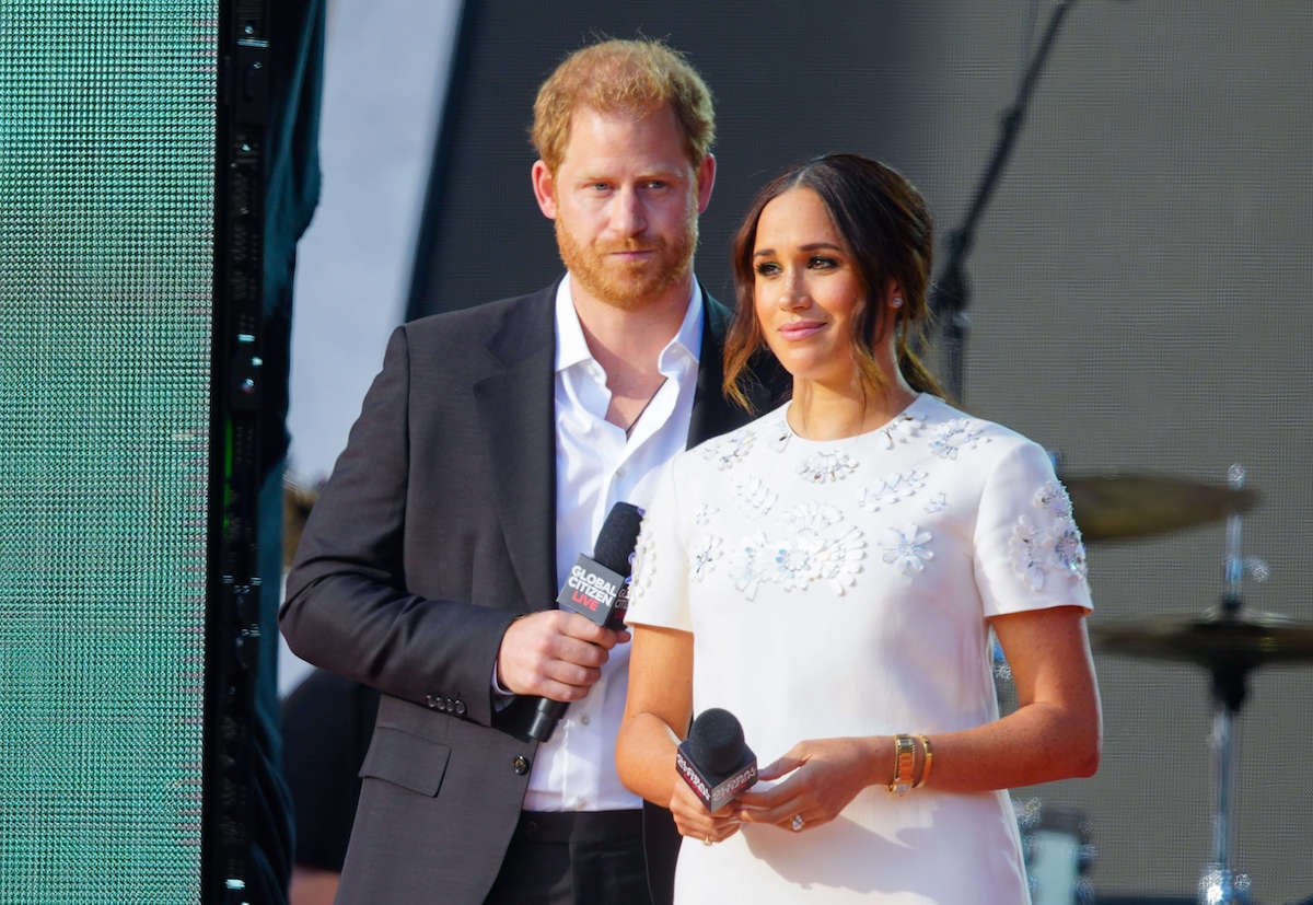 Meghan Markle and Prince Harry, who, according to a historian have shown they can 'put personal enmity aside' for King Charles' coronation, stand together and look on