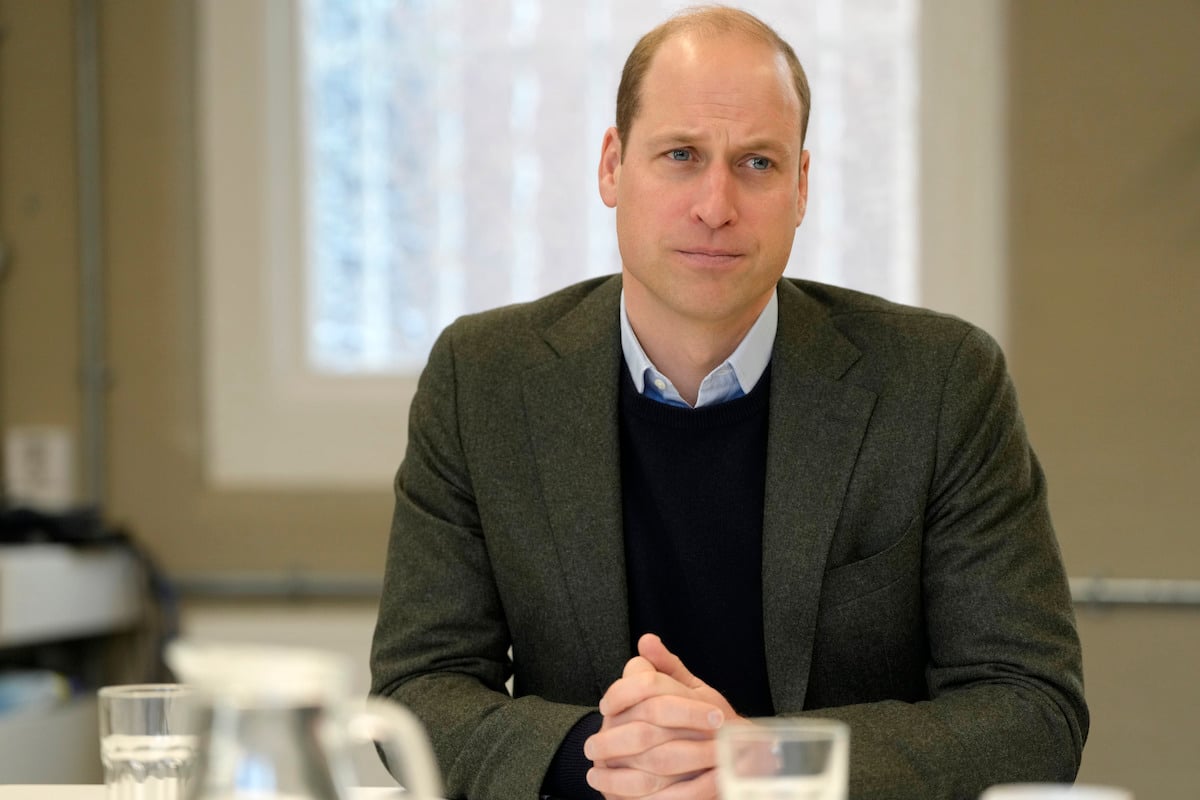 Prince William in a grey jacket with his hands folded