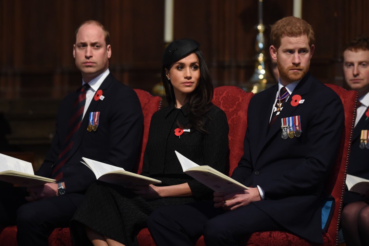 Prince William, Meghan Markle, and Prince Harry sit together.