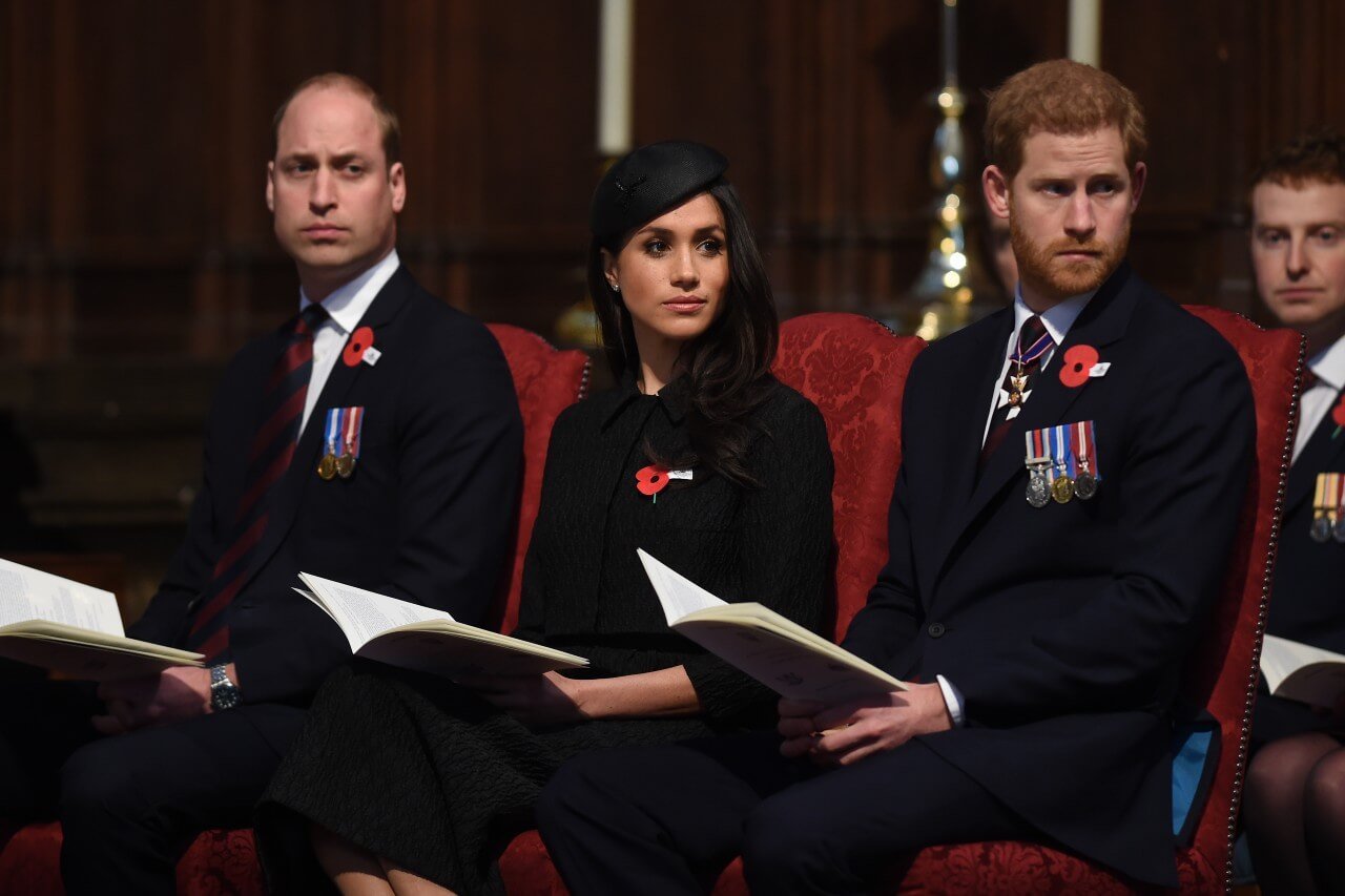 Prince William, Meghan Markle, and Prince Harry sit together. 