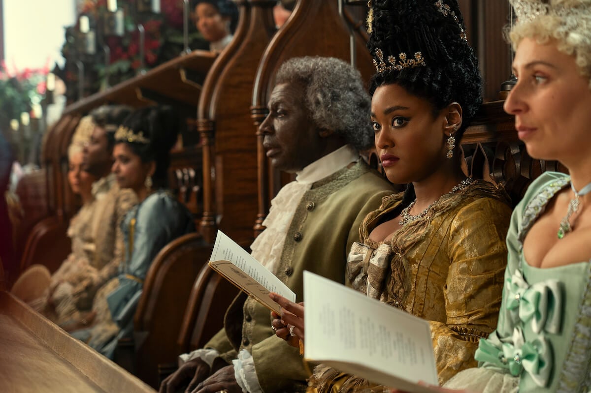 Cyril Nri as Lord Danbury, and Arsema Thomas as Young Agatha Danbury sitting in a cathedral in 'Queen Charlotte: A Bridgerton'