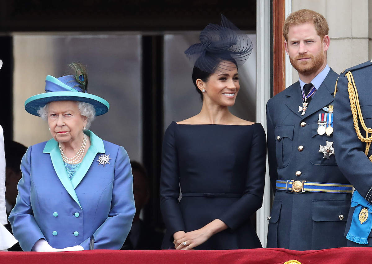 Meghan Markle, who gifted Prince Harry a Queen Elizabeth ornament, stands next to Queen Elizabeth and Prince Harry 