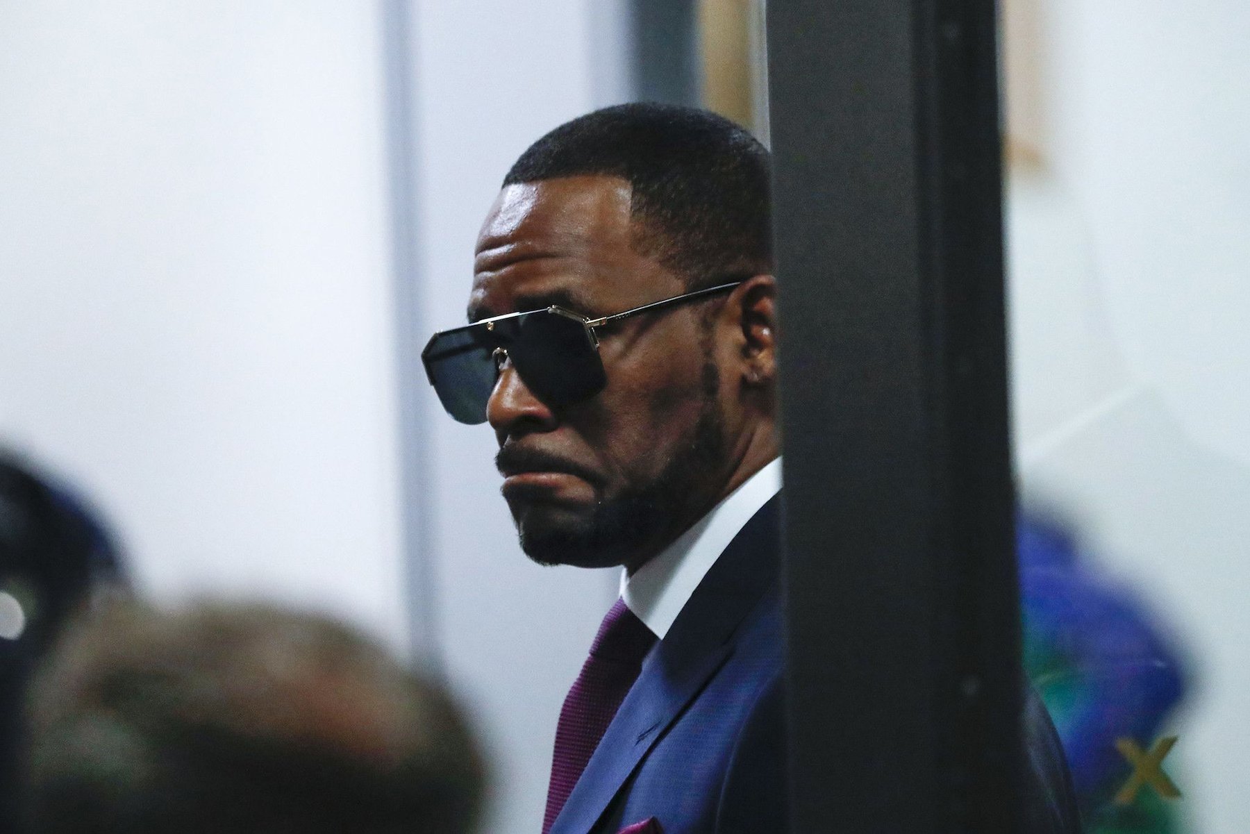R. Kelly, who has faced abuse allegations in recent years, wears sunglasses and a navy suit