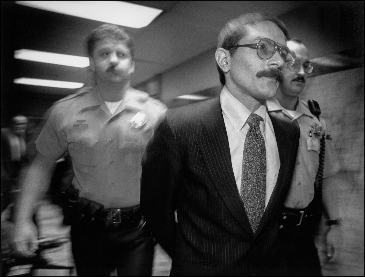 Black and white photo of Randy Roth being led into court