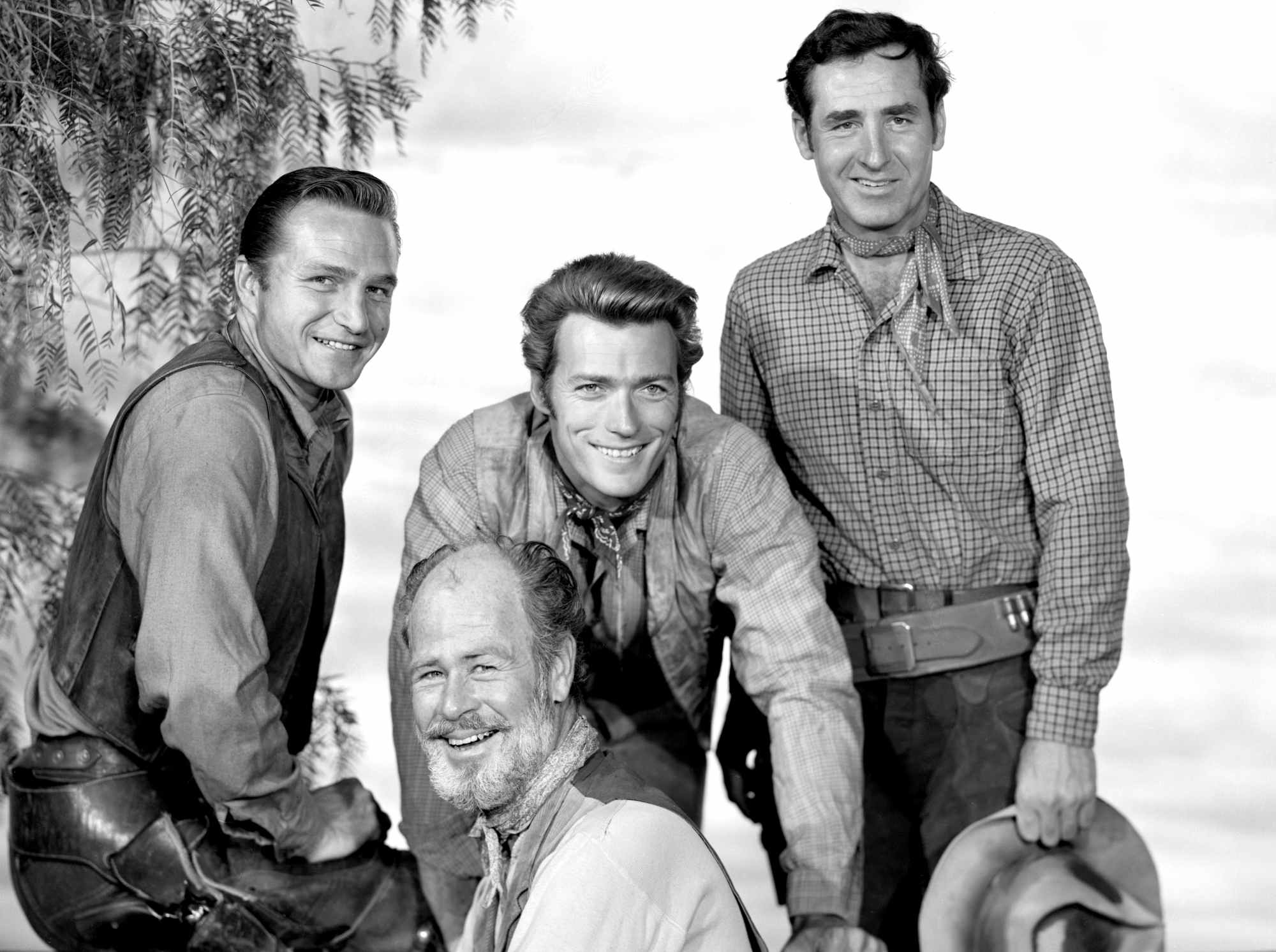 'Rawhide' Eric Fleming as Gil Favor, Paul Brinegar as Wishbone, Clint Eastwood as Rowdy Yates, and Sheb Wooley as Pete Nolan wearing Western costumes, smiling for a promo image.