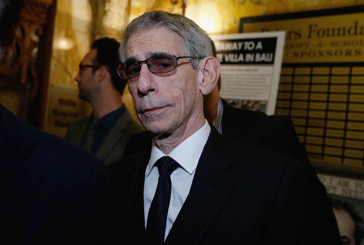 Richard Belzer poses in sunglasses and a black suit during an event.
