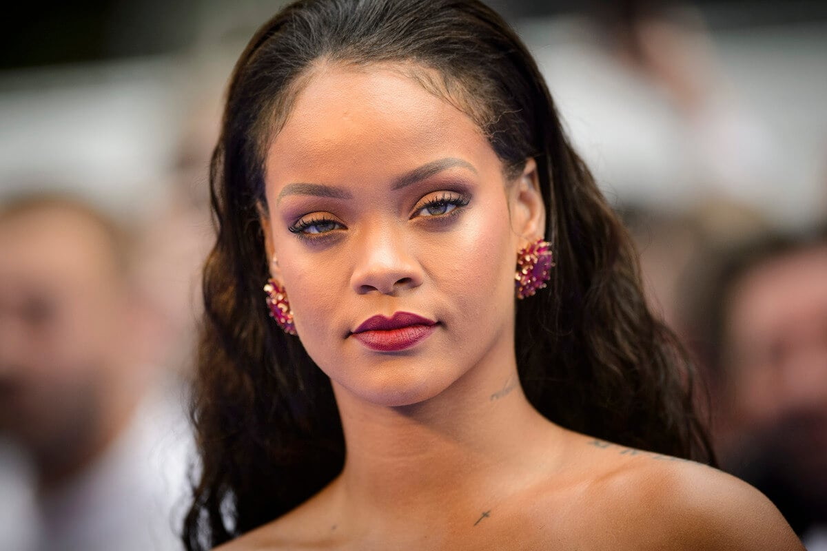 Rihanna poses wearing red earrings at an event.
